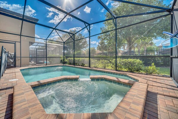 A swimming pool with a brick border and a glass enclosure.