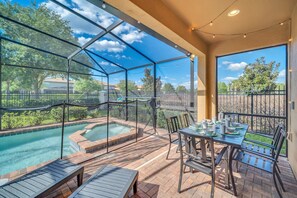 A covered outdoor area with a pool, patio furniture, and a table set for dining.