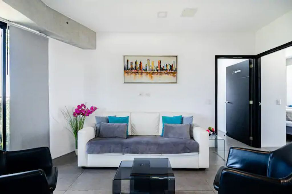 Una sala de estar moderna con un sofá blanco, una mesa de centro negra y un cuadro en la pared.