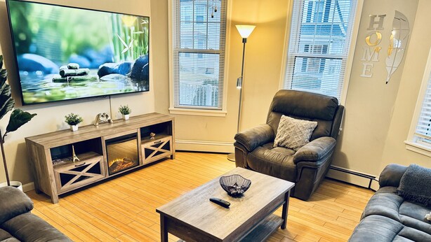 Un salon avec une table basse en bois, un canapé en cuir et un téléviseur posé sur un meuble en bois.