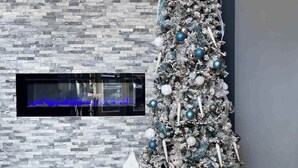 Un salon moderne agrémenté d’un grand sapin de Noël décoré, d’une cheminée et de luminaires contemporains.