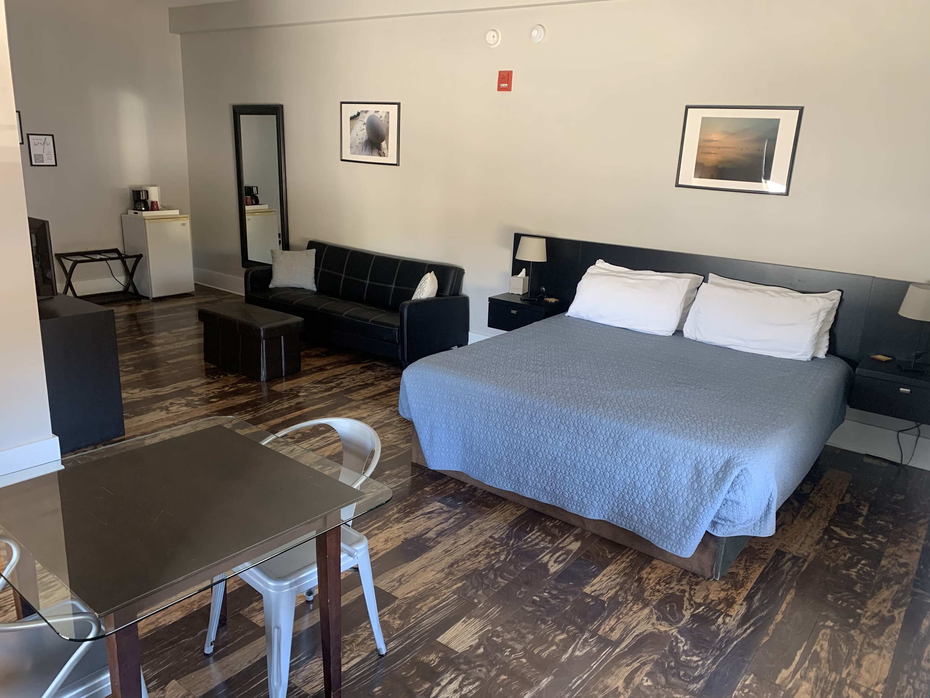 Ein Hotelzimmer mit Bett, Schreibtisch, Sessel, Sofa und kleinem Tisch.