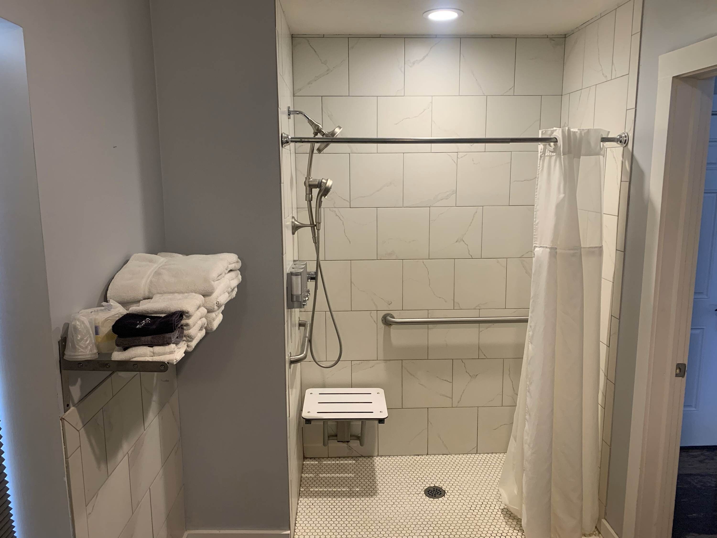 A walk-in shower with a glass door, tiled walls, a towel rack, and a shower control panel.