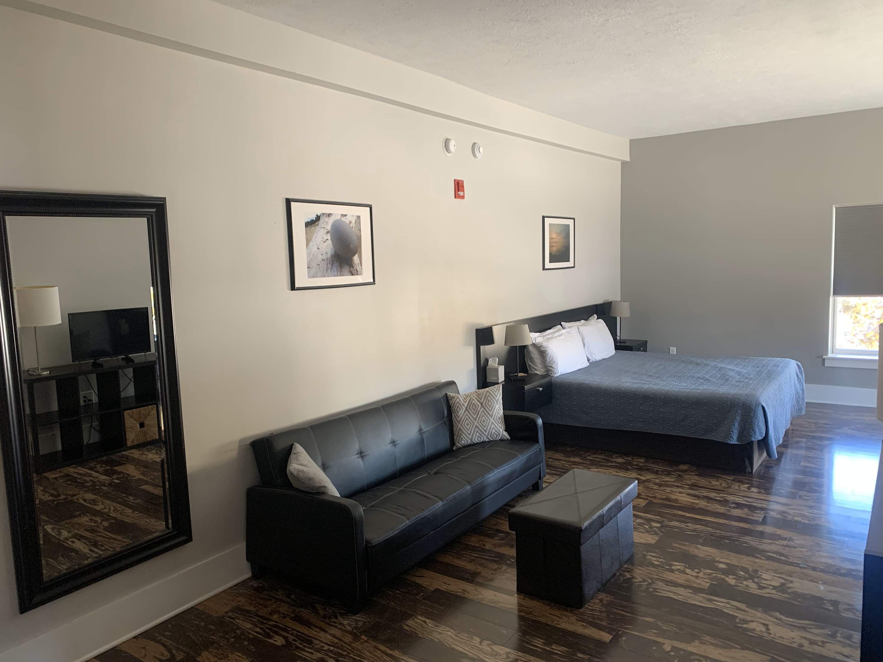 Ein Hotelzimmer mit einem großen Bett, einer Couch, einem kleinen Tisch und einem Spiegel.
