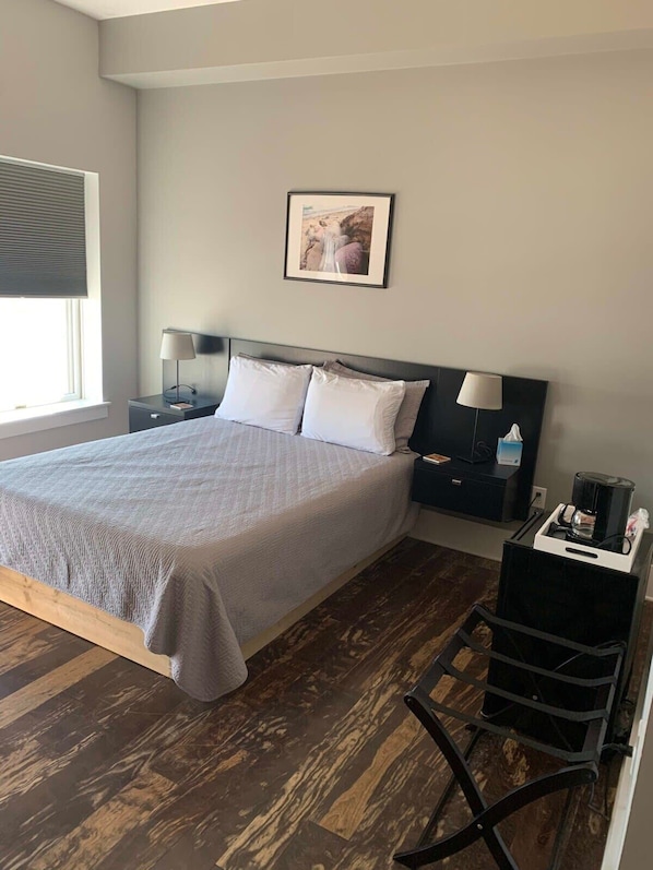 Relax in a serene space with a large bed, framed artwork, and a comfortable chair.