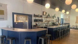 A bar area with stools, a counter, and shelves with bottles. - Northport Inn Boutique Hotel Room 4 (Northport)
