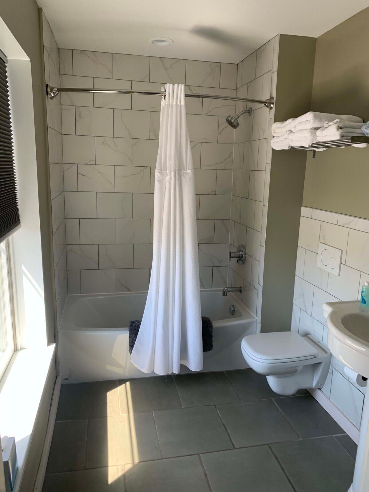 A bathroom with a shower, toilet, and sink.