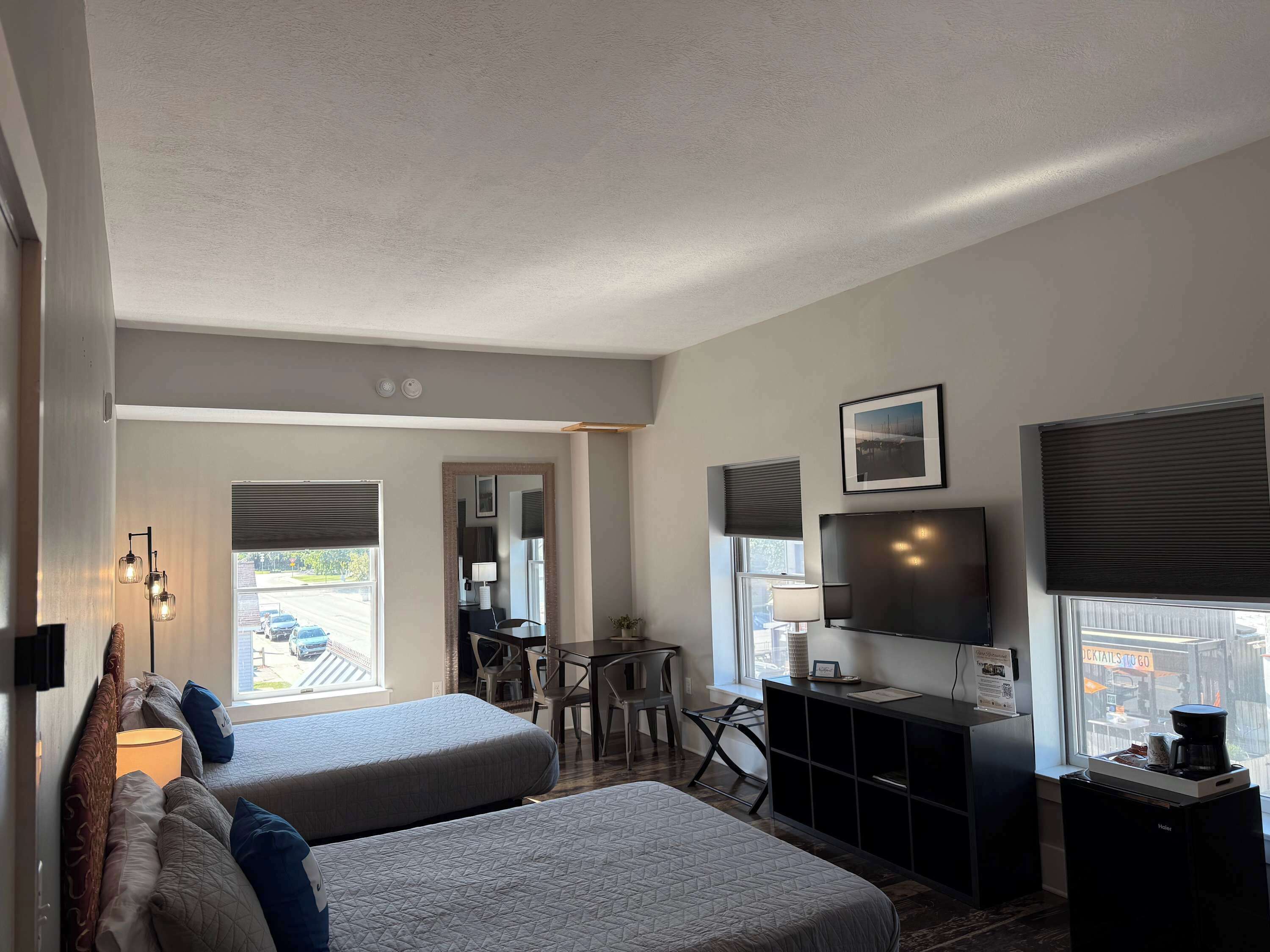 Habitación de hotel con dos camas, un escritorio, un televisor y una ventana con vista a la calle.