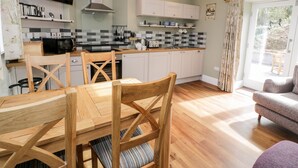Une cuisine moderne avec des meubles en bois, un téléviseur à écran plat et un coin repas comprenant une table et des chaises.