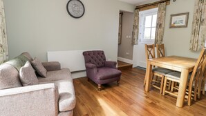 Un salon comprenant un canapé, un fauteuil, une table à manger et des chaises.