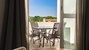 A balcony with a table and chairs, a view of trees and buildings, and a clear sky. - Villa Paraiso Da Caparica (Almada)