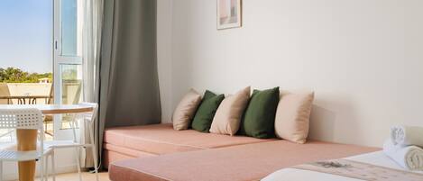 Una habitación de hotel moderna con sofá cama, una pequeña mesa y sillas, y vistas al exterior.