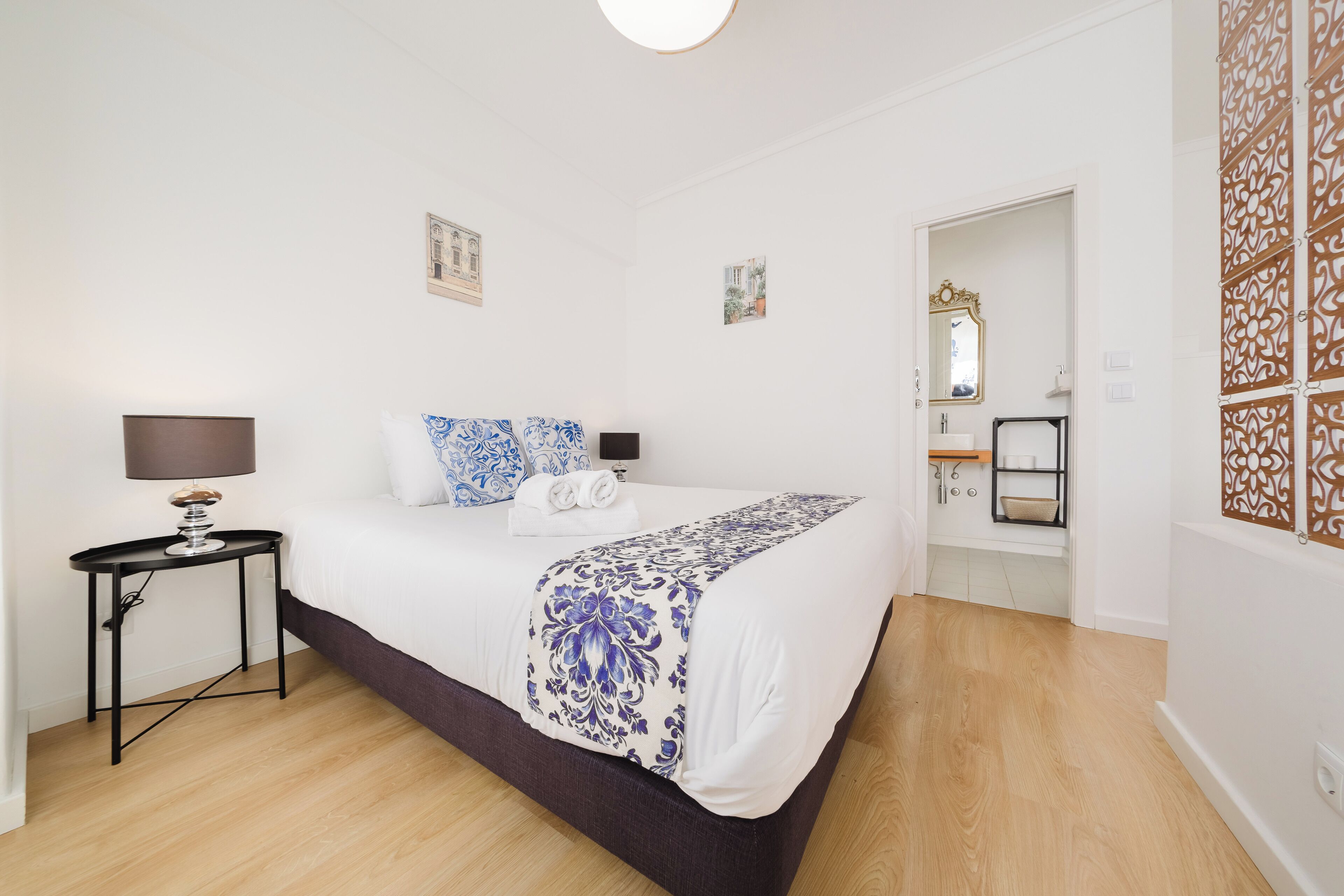 A bedroom with a bed, bedside tables, a lamp, and a mirror.