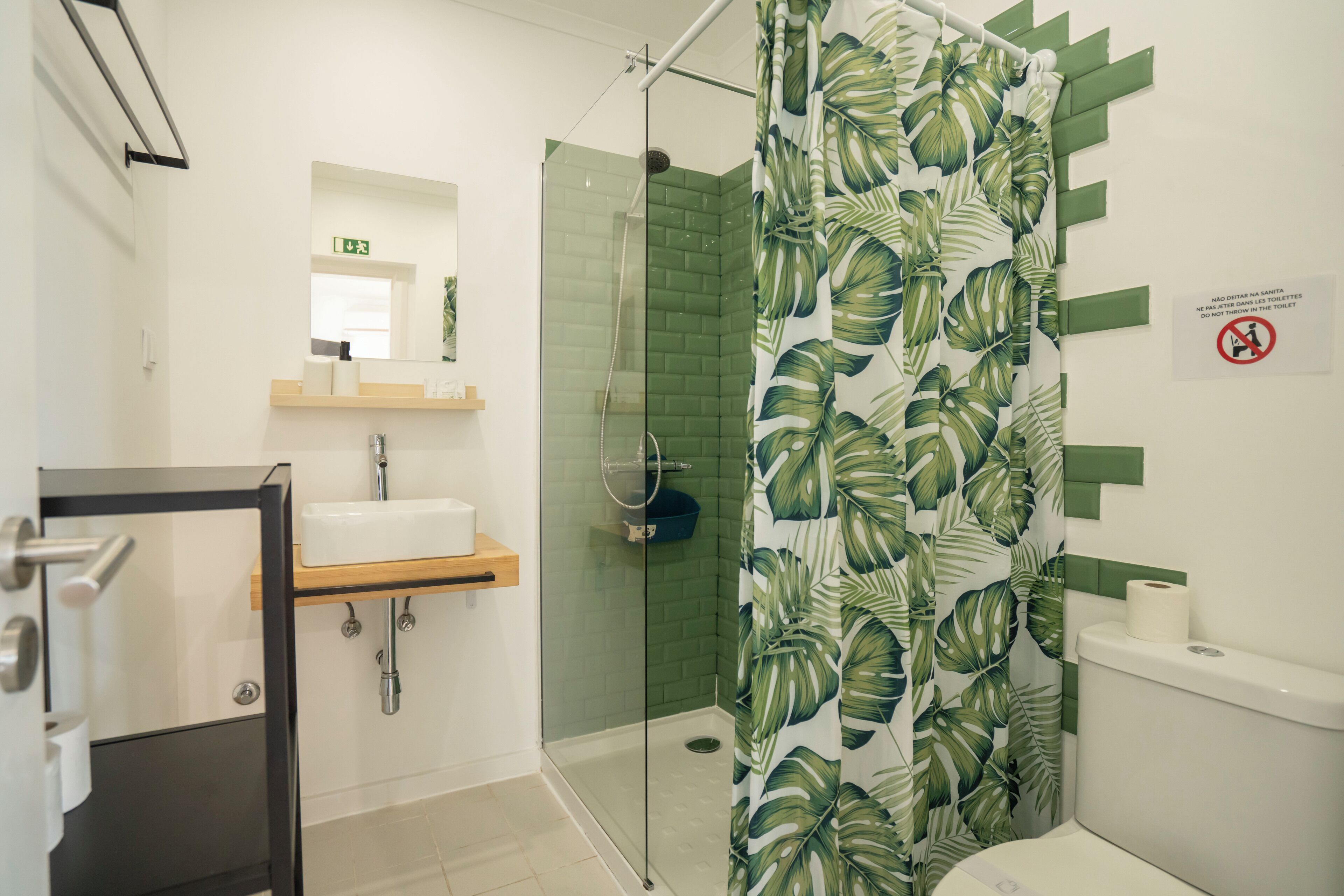 A modern bathroom with a glass shower enclosure, a sink with a wooden shelf, and a toilet.