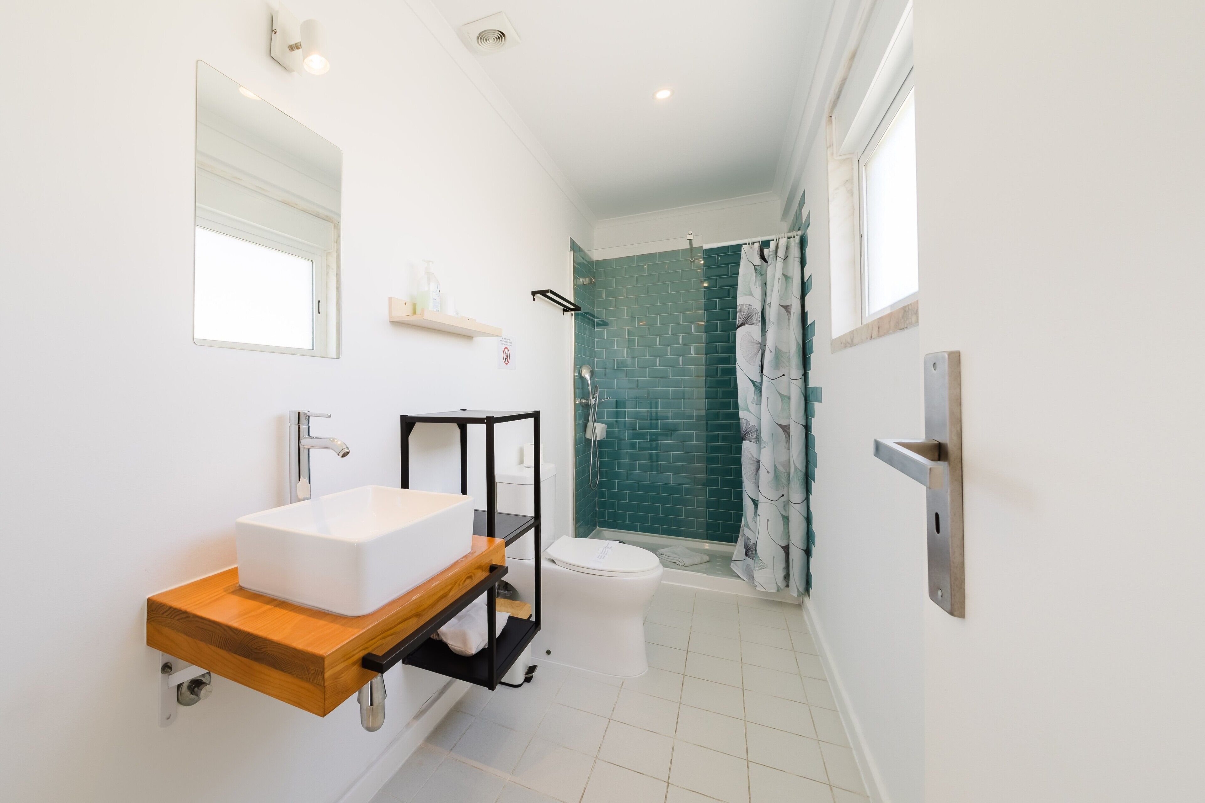 A modern bathroom with a white sink, a mirror, a shower with a glass door, and a toilet.
