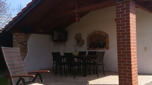 Un patio techado al aire libre con chimenea de ladrillo, una mesa de comedor y sillas.