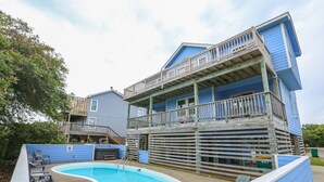 Un bâtiment à deux étages doté d’une piscine et d’un espace extérieur aménagé pour s’asseoir.