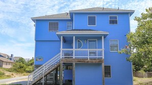Une maison bleue à deux étages, dotée d’un balcon, d’un escalier et d’un petit porche.