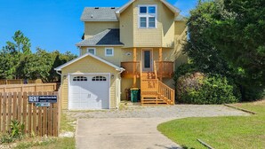 A two-story house with a garage, a wooden deck, and a paved driveway. - Top Of THe Hill - High Dune location, 4 BR home w/Private Pool and Dogs Allowed (Southern Shores)
