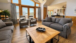 Un salón amplio con una mesa de centro de madera, sofás grises y una zona de comedor con mesa y sillas.