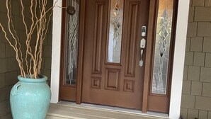A brown double door with a glass panel and a keyhole, a large blue vase with branches, and a small step leading to the door.