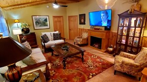 A cozy living room with a fireplace, a television, and a decorative cabinet.