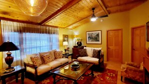 A cozy living room with a sofa, armchair, coffee table, and a ceiling fan.