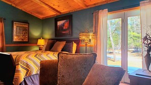 A room with a bed, a chair, a lamp, and a painting on the wall.