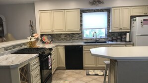 Une cuisine moderne avec des meubles blancs, un lave-vaisselle noir et un pare-feu en carrelage.