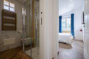 A modern bathroom with a glass shower enclosure, a toilet, and a towel rack. - Villa in the Blue Suite with a balcony (Campania)