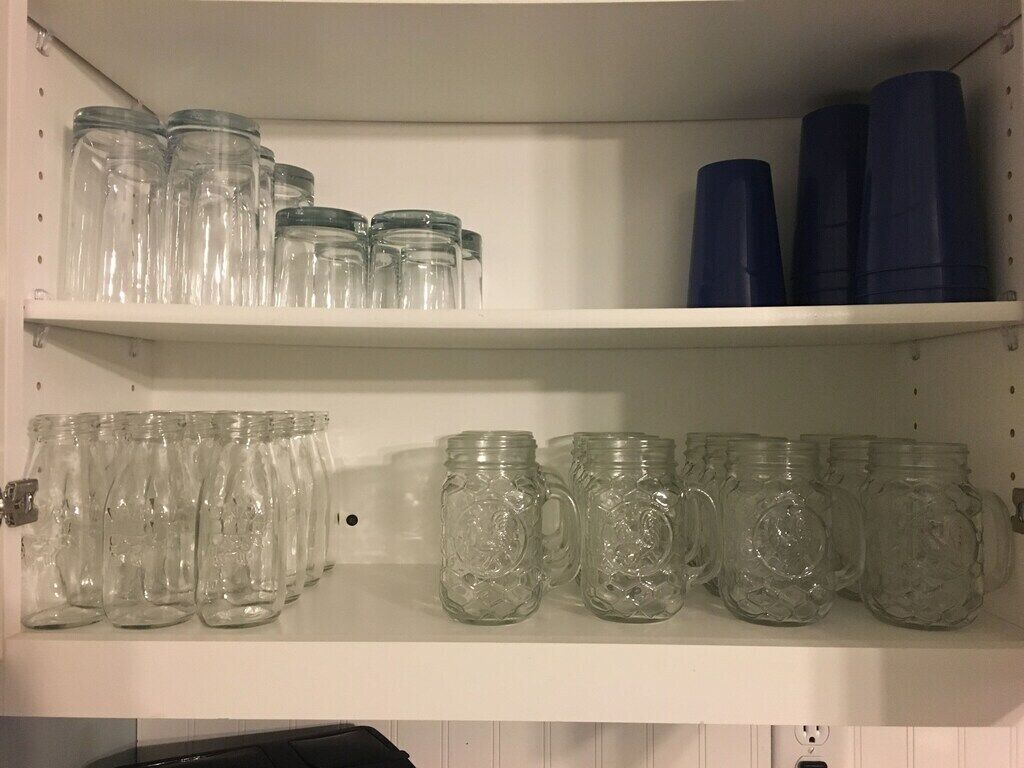 Deux étagères avec des bocaux en verre et des tasses.