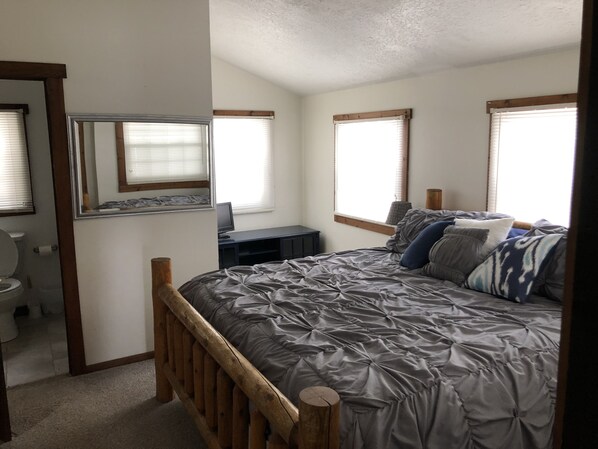 A bedroom with a wooden bed frame, a desk with a computer, and a window with blinds. - Amish country Farmhouse in quiet Holmes County with fishing (Killbuck)