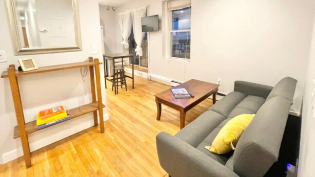 A living room with a sofa, a coffee table, a TV, and a dining area with a table and chairs. - North End, Lil Italy, TD Garden (Boston)