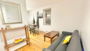 A living room with a grey sofa, wooden coffee table, and a TV on the wall. - North End, Lil Italy, TD Garden (Boston)