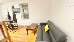 A living room with a sofa, a wooden coffee table, and a dining area with chairs and a table. - North End, Lil Italy, TD Garden (Boston)