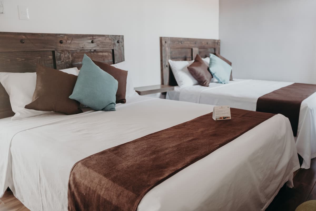 Two single beds with wooden headboards, white bedding, and brown throw blankets.