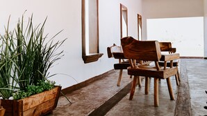 A wooden bench and chairs in a room with a concrete floor and white walls. - Hacienda Viga 2020 Hotel (Cuatro Ciénegas)
