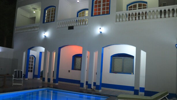 A pool area with a clear blue pool, lounge chairs, and a chair. - Orient star hotel (Luxor)