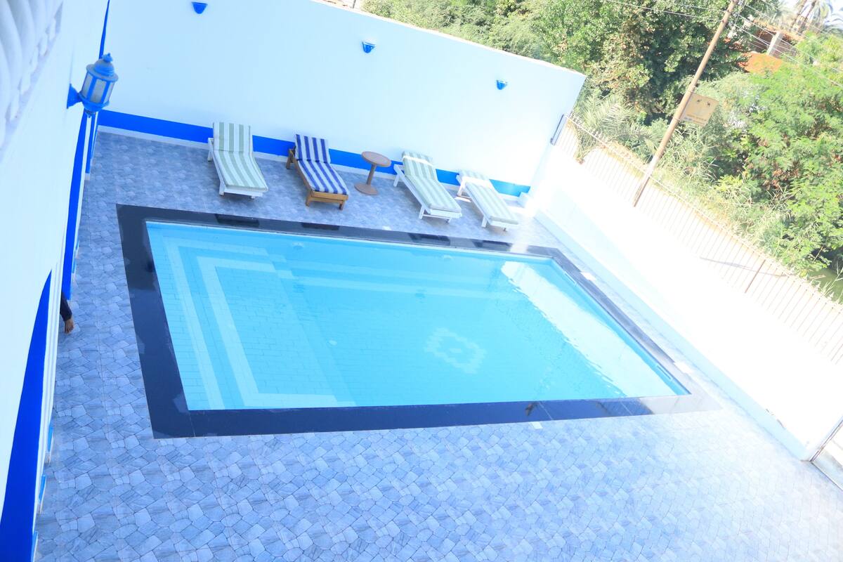 A swimming pool with lounge chairs and a tiled deck.