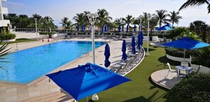 Relax by the serene pool surrounded by palm trees and lounge chairs.