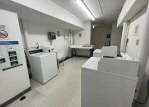 Convenient laundry facility with multiple washing machines and dryers, a sink, and a table for efficient laundry tasks.