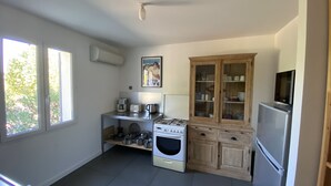 Eine kleine Küche mit Gasherd, Backofen, Kaffeemaschine und einem Schrank mit Glastüren.