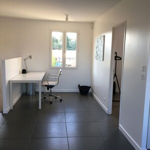 A small, modern room with a white desk, a chair, a floor lamp, and a window with a view of trees. - Spacious holidayhouse with terrace and Mont Ventoux view (Entrechaux)