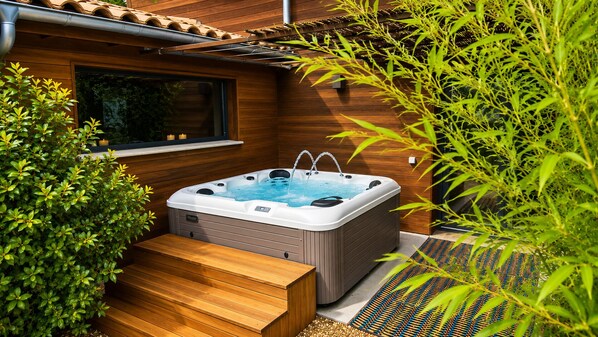A hot tub in a wooden outdoor area with steps leading up to it.