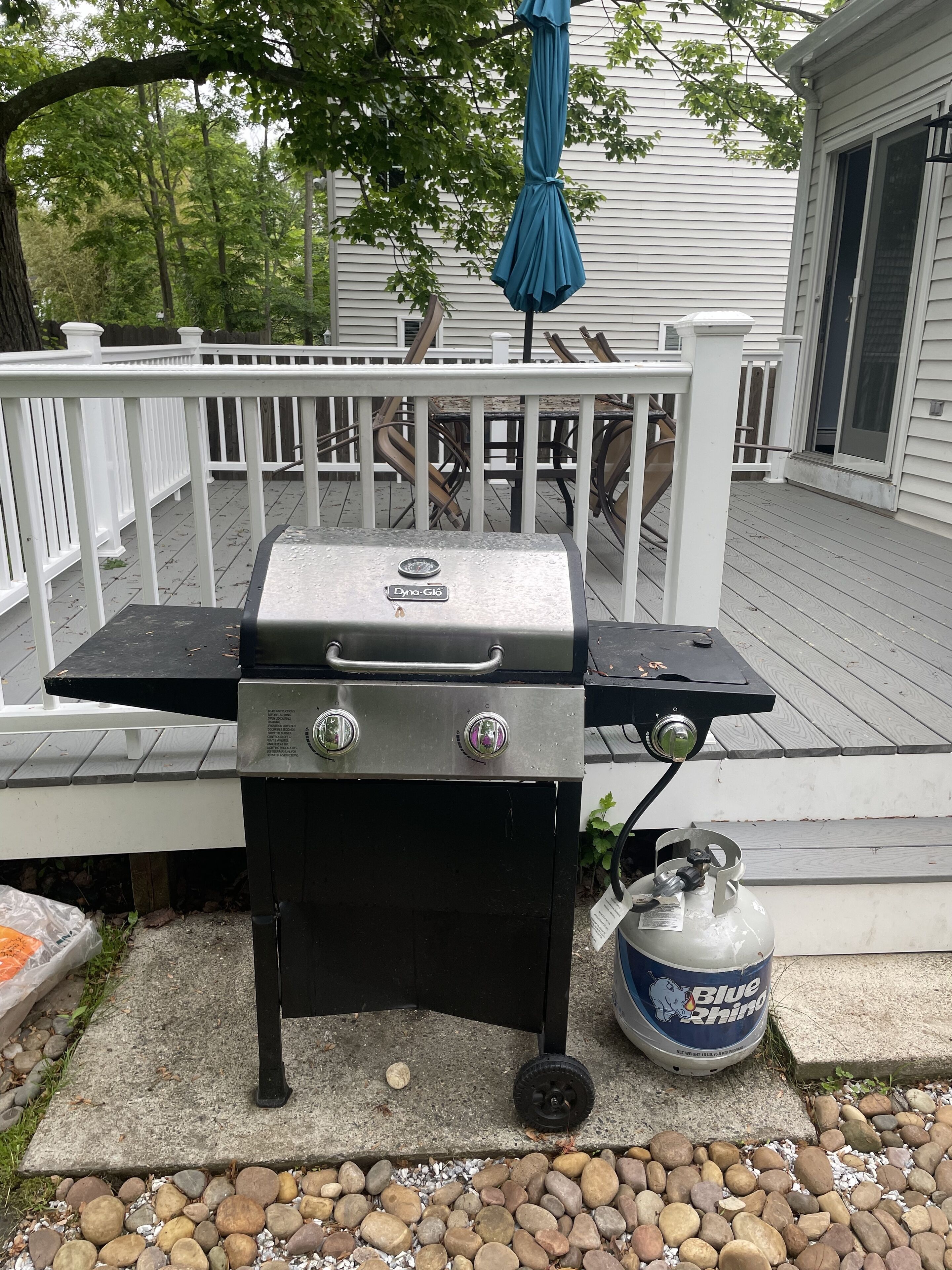 Un barbecue portatif avec une bouteille de gaz, installé sur une terrasse.