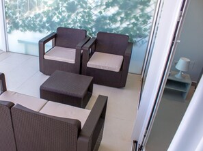 Relax in an outdoor space with a sofa, table, and lamp, surrounded by lush greenery.