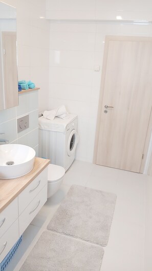 Een bad/douchecombinatie, een bubbelbad, een haardroger, handdoeken