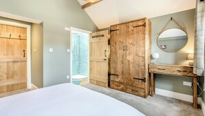 Quarto com cama grande, armário de madeira e banheiro com chuveiro.