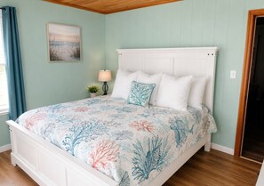 A bedroom with a bed, a nightstand, a lamp, and a painting on the wall.