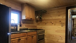 Een keuken met houten kastjes, een fornuis en een raam.